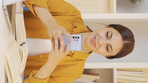 Young Woman Photographs Book with Smartphone
