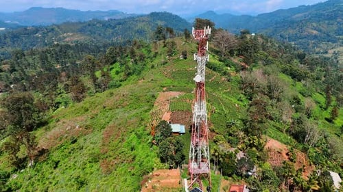 Telecommunication tower located on the hill. Beautiful mountainous area overgrown with lush greenery