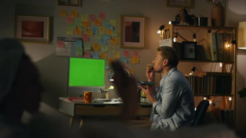 Man Eating at Desk with Green Screen Monitor