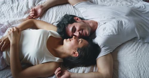 Attractive Couple Laying Down on Bed and Smiling