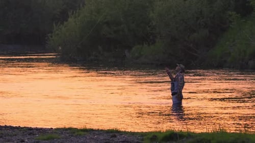 Fly fishing. Fisherman casts fly on the river at sunset. Caucasian amateur angler fishing on the riv