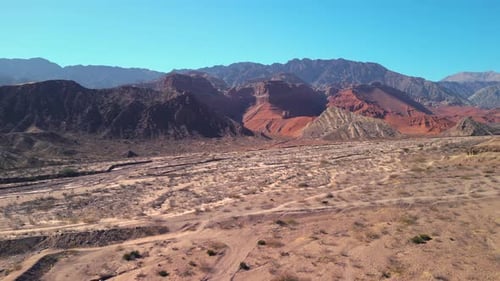 Aerial view drone flying over scenic red rocky mountains landscape with a clear blue sky.