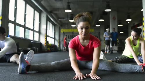 Young People in Crossfit Gym Stretching Their Legs