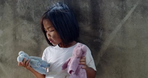 A 5-year-old Asian girl from rural Thailand, ovingly holds a DIY doll made from fabric scraps