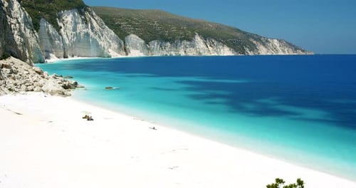 Secluded Fteri beach on Keflaonia Island, Greece. White rocks and blue lagoon surrounded by green fo