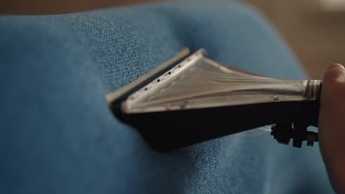 Close up of cleaning machine cleaning blue upholstery
