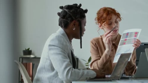 Women Analyzing Charts and Data in Workplace