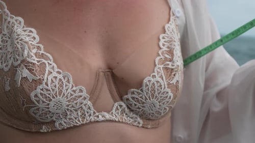 Woman Measures Bust with Tape Measure on Beach