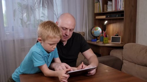 Portrait of a Happy Father with a Tablet and His Little Son at Home