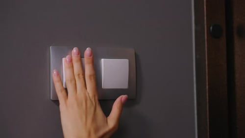 Closeup de uma mulher ligando o interruptor de luz em um quarto escuro