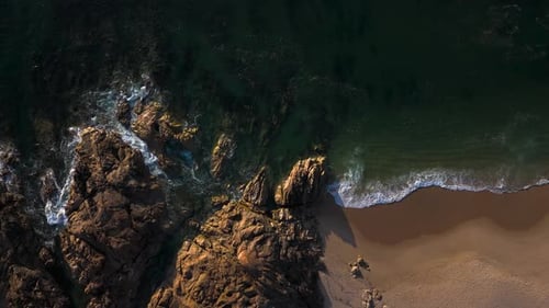 beautiful rocky and sandy beach with calm sea waves, aerial drone view