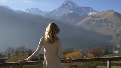 slender woman stands with her back on the terrace overlooking the mountains
