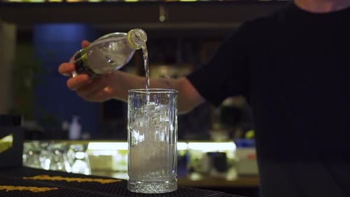 Bartender Pouring Liquid into Glass with Ice