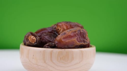 Brown Dates Filling Wooden Bowl on Green Screen