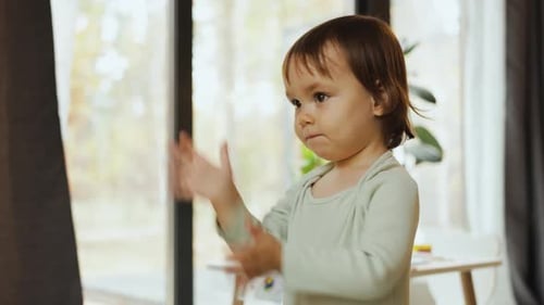 Happy Child Clapping Hands Waving in Bright Room