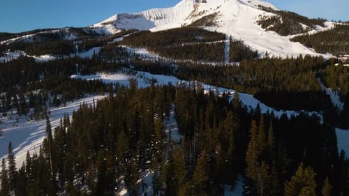 A drone shot of snowy Big Sky, Montana in winter, showcasing the ski resort and majestic mountain te