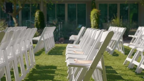 Green lawn with rows of wooden chairs. Place for a wedding ceremony. Marriage reception