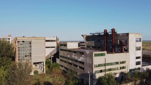 Pedestal drone shot revealing an abandoned former rare metals enterprise located near a fishing vill