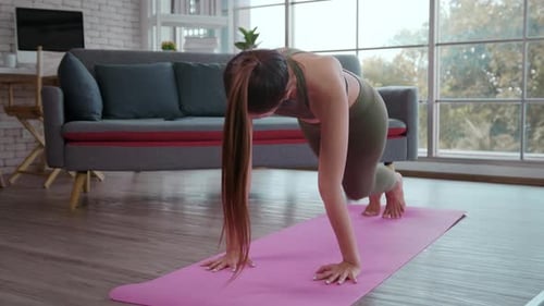 Young fitness woman in sportswear exercising at home