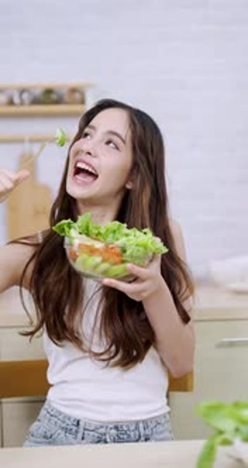 Smiling Woman Enjoys Fresh Salad in Modern Kitchen