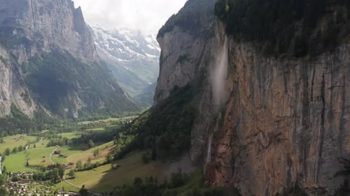 Flying up to waterfall pouring out of rocky mountainside