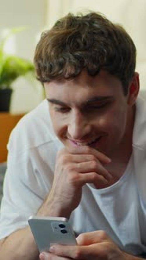 Man Smiles While Using Smartphone Indoors