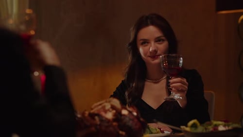 A Beautiful Young Woman in an Evening Dress Sits at a Table with a Glass of Red Wine and Talks to