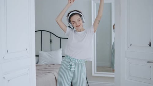 Carefree Woman Dancing to Music in Bedroom