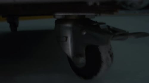 Small Wheel of Janitor Cart Driving Along Dark Ice Arena