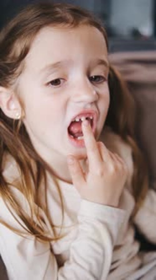 Vertical Video The Child Shakes the Front Baby Tooth and Smiles a Toothless Smile Closeup Changing