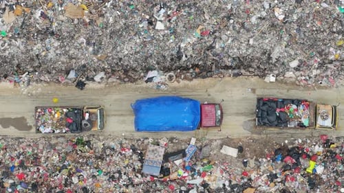 Aerial top down view of garbage trucks moving through a large landfill