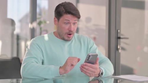 Man Surprised by Good News on Smartphone