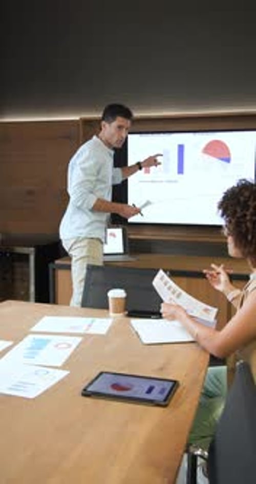 Receiving printed reports, Diverse coworkers discussing data and pointing at graphs in boardroom