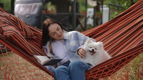 Woman Reading with her Dog in Hammock