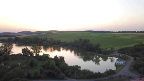 Flying On The Idyllic View Of A Pond Surrounded By Evergreen Landscape. Aerial Drone