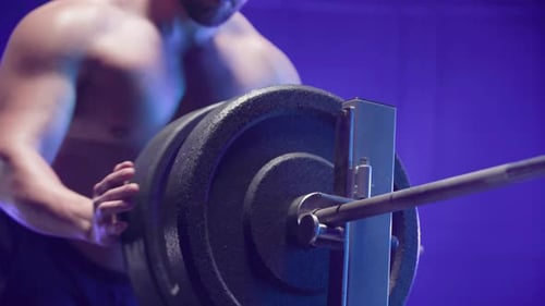 Shirtless Man Adds Weights to Barbell for Workout