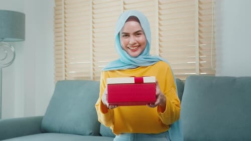 Young surprised muslim woman opening a gift