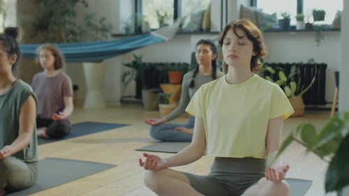 Group Meditates During Yoga Class in Sunny Studio