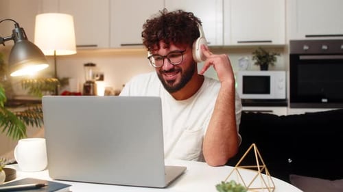 Arabian Man in Headphones Listens Instrumental Music Types Soft Pace Writes Tomorrow Plan Relaxed