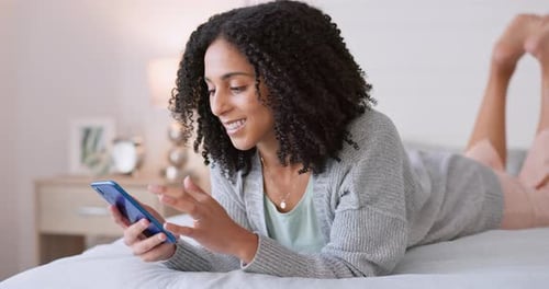 Social media, phone and bed with young black woman relax, smile and online lying in bedroom at home