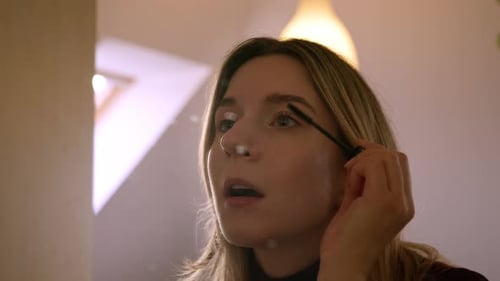 Woman Applies Mascara in the Mirror