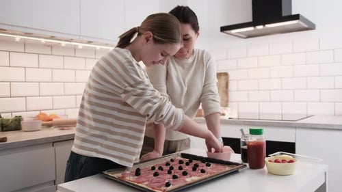 Teen and Woman Making Pizza in White Kitchen