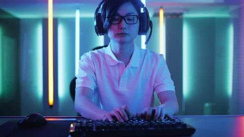 Focused Man Gaming Online in Neon Lit Room