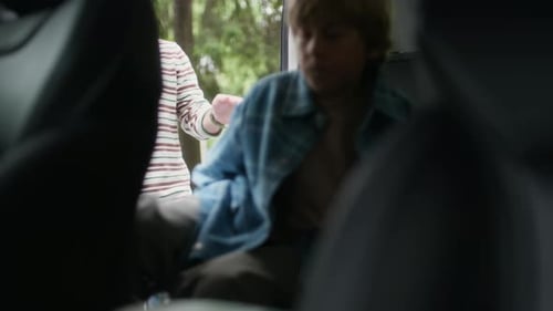 Boy Sitting Down on Backseat while His Father Helping Him Fasten Seatbelt