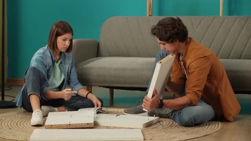 Close Up of Apartment Living Room Couple Assembles New Furniture Woman Reads Instruction Man Puts
