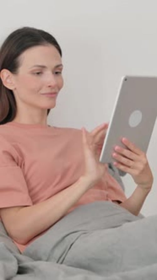 Woman Relaxing in Bed Using Digital Tablet
