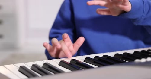 Child Practices Piano Keyboard at Home Close Up