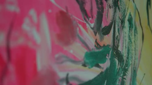 Close-up view of vibrant abstract brushstrokes with a mix of pink, green, and yellow hues creating a