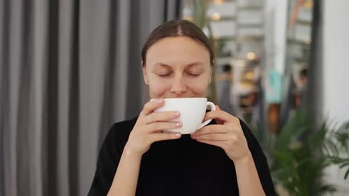 Young Woman Smiling and Smelling Coffee Indoors