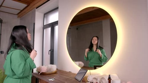 Woman Trimming Hair in Bright Bathroom Mirror